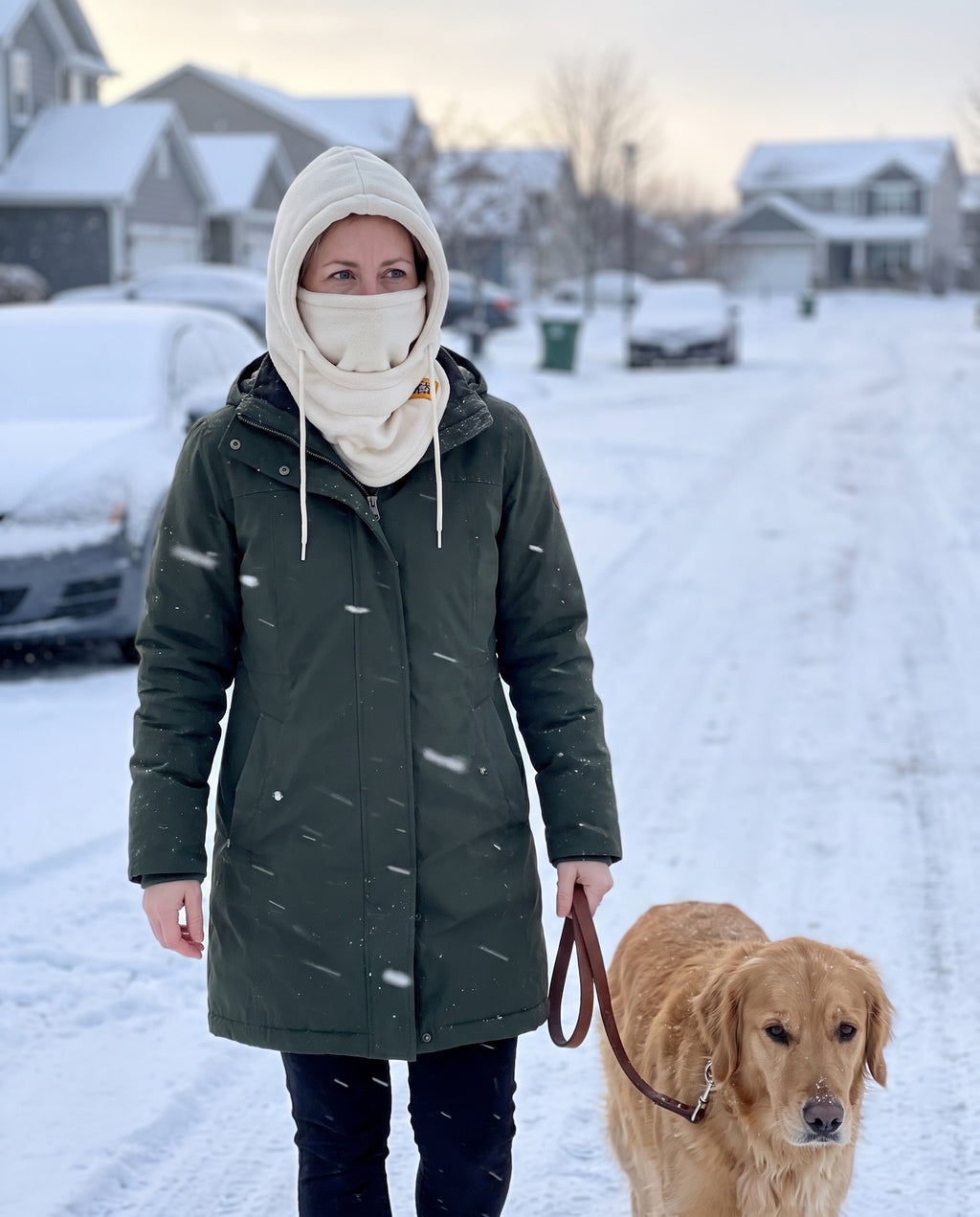 Woman walking her dog on a snowy street wearing the cream fleece hood