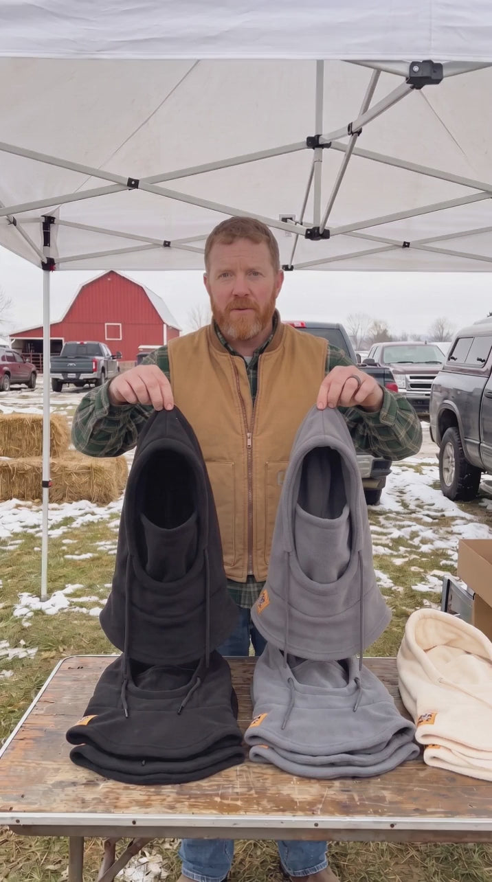 Vendor at a winter farm show demonstrating the Halefield fleece hood two-pack